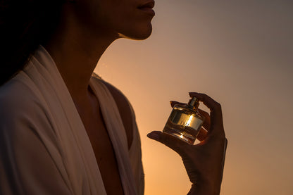 A woman holding a bottle of Delos eau de parfume.