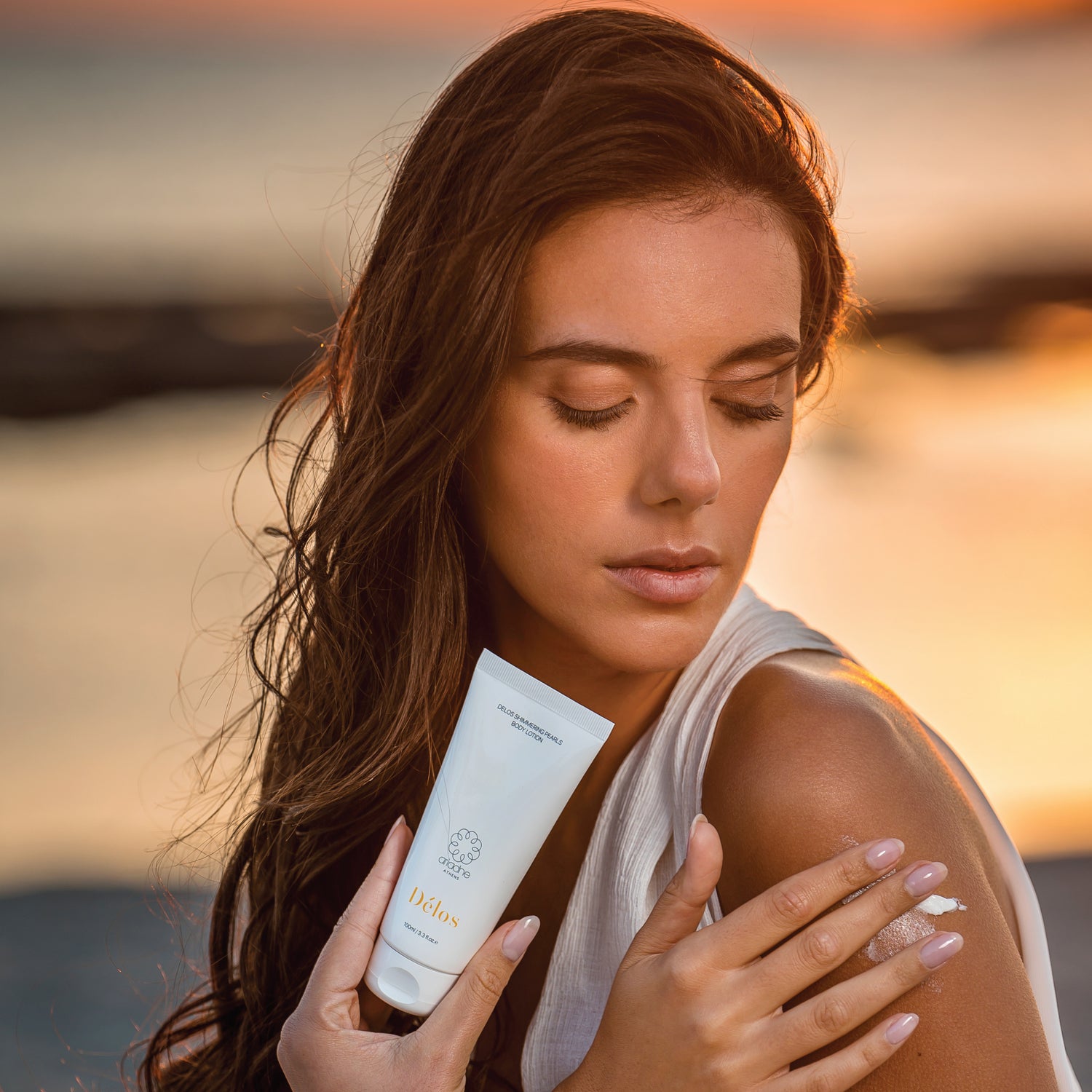 A woman applying Délos Shimmering Pearls Body Lotion.