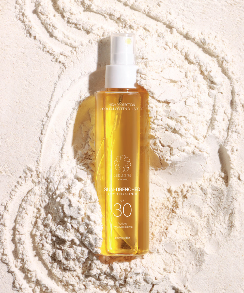A  bottle of Sun Drenched Body sunscreen oil on the sand.